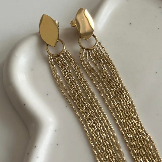 Détail des boucles d’oreilles Jodie dorées en acier inoxydable 316L avec multiples chaînes fines pendantes.