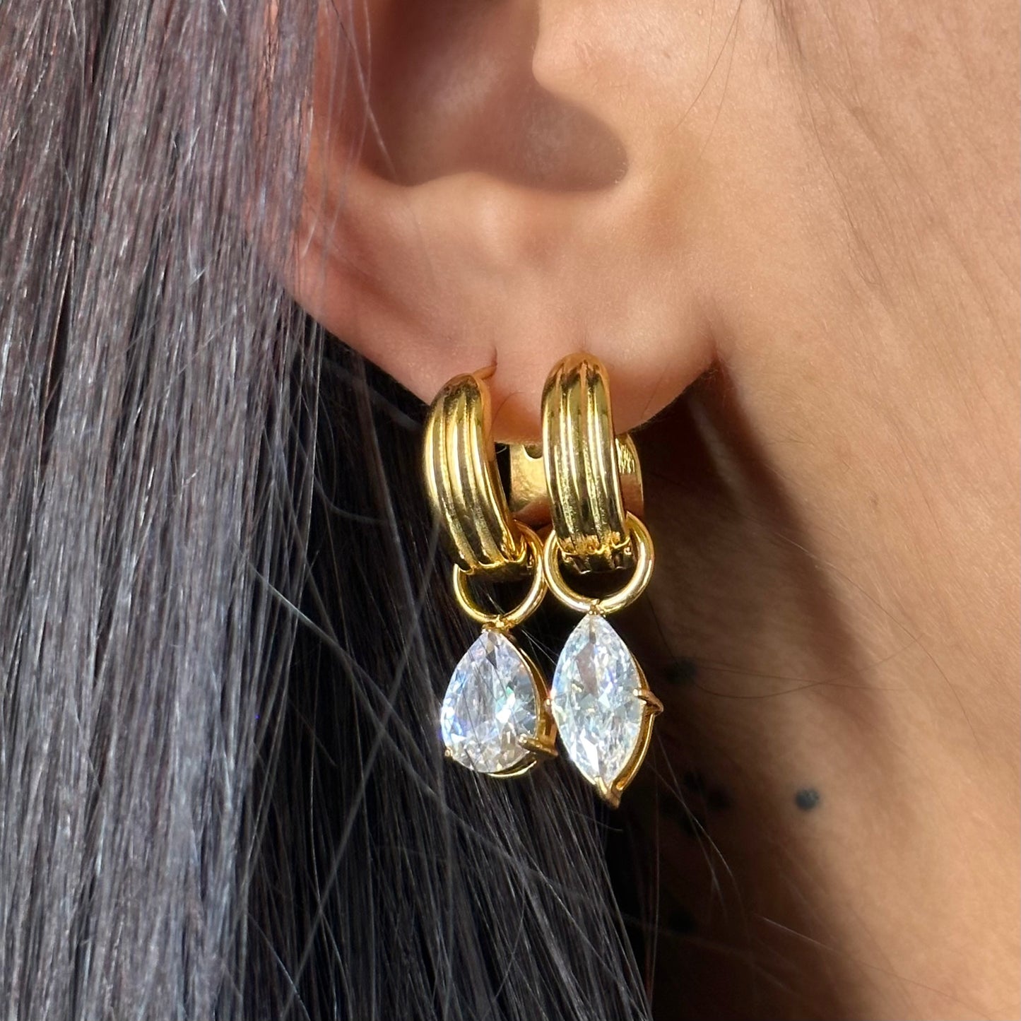 Paire de boucles Alix en acier inoxydable plaqué or 18K avec pendants zircons asymétriques portées.