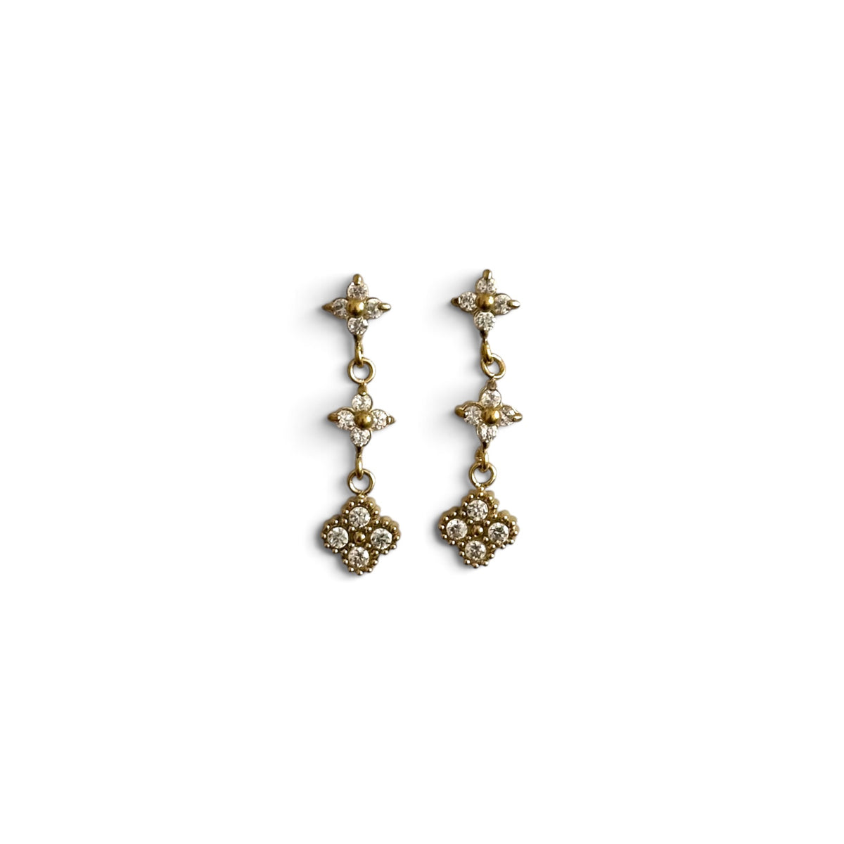 Boucles d’oreilles Line dorées pendantes ornées de zircons sur fond blanc.