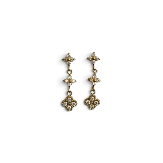 Boucles d’oreilles Line dorées pendantes ornées de zircons sur fond blanc.