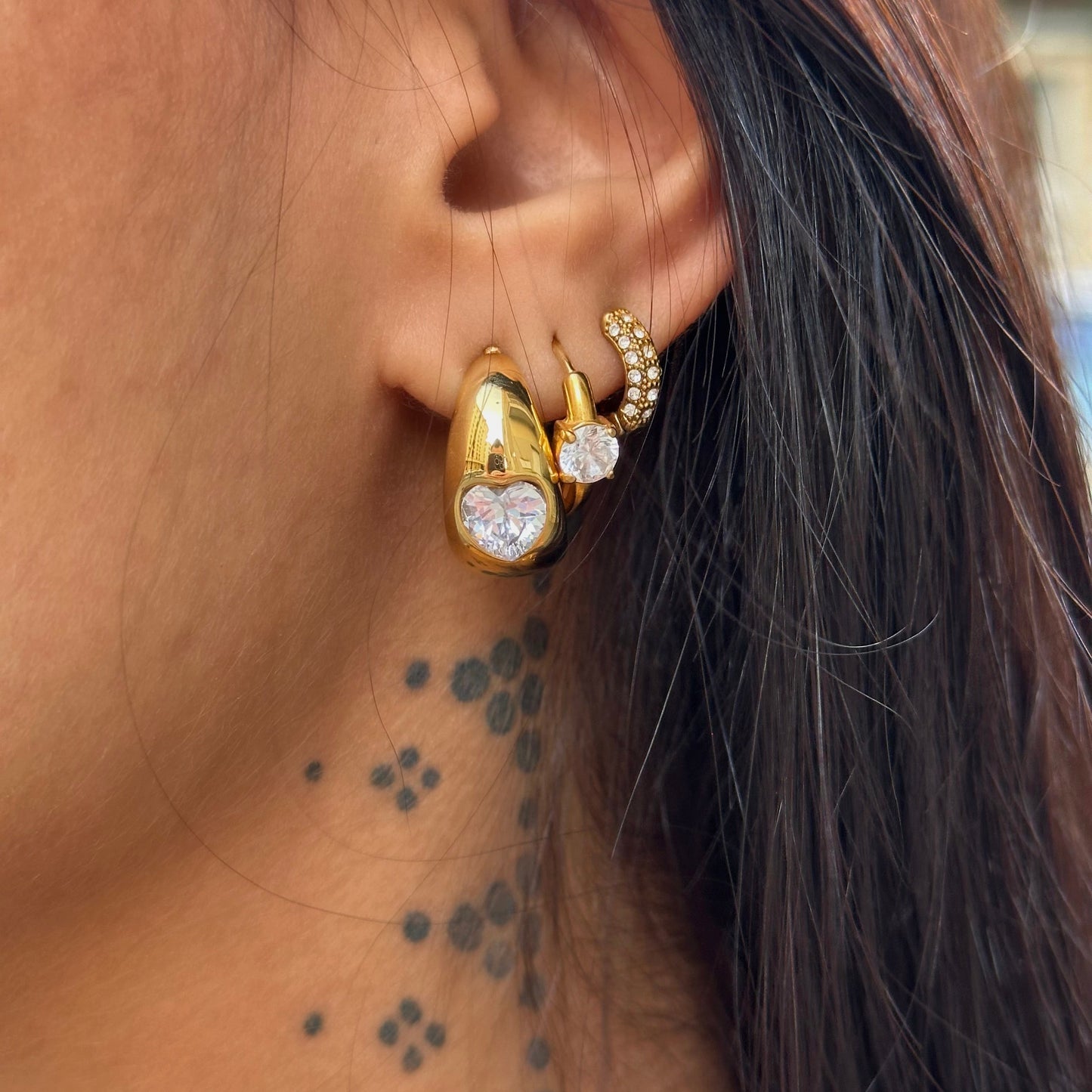 Boucles d’oreilles Tahia dorées en acier inoxydable avec zircon en forme de cœur portées.
