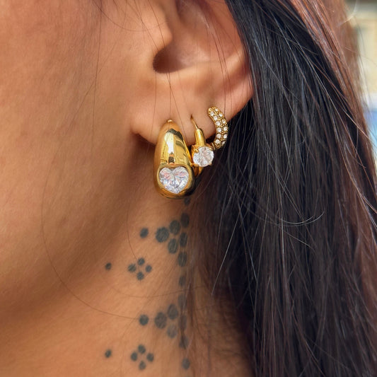 Boucles d’oreilles Tahia dorées en acier inoxydable avec zircon en forme de cœur portées.