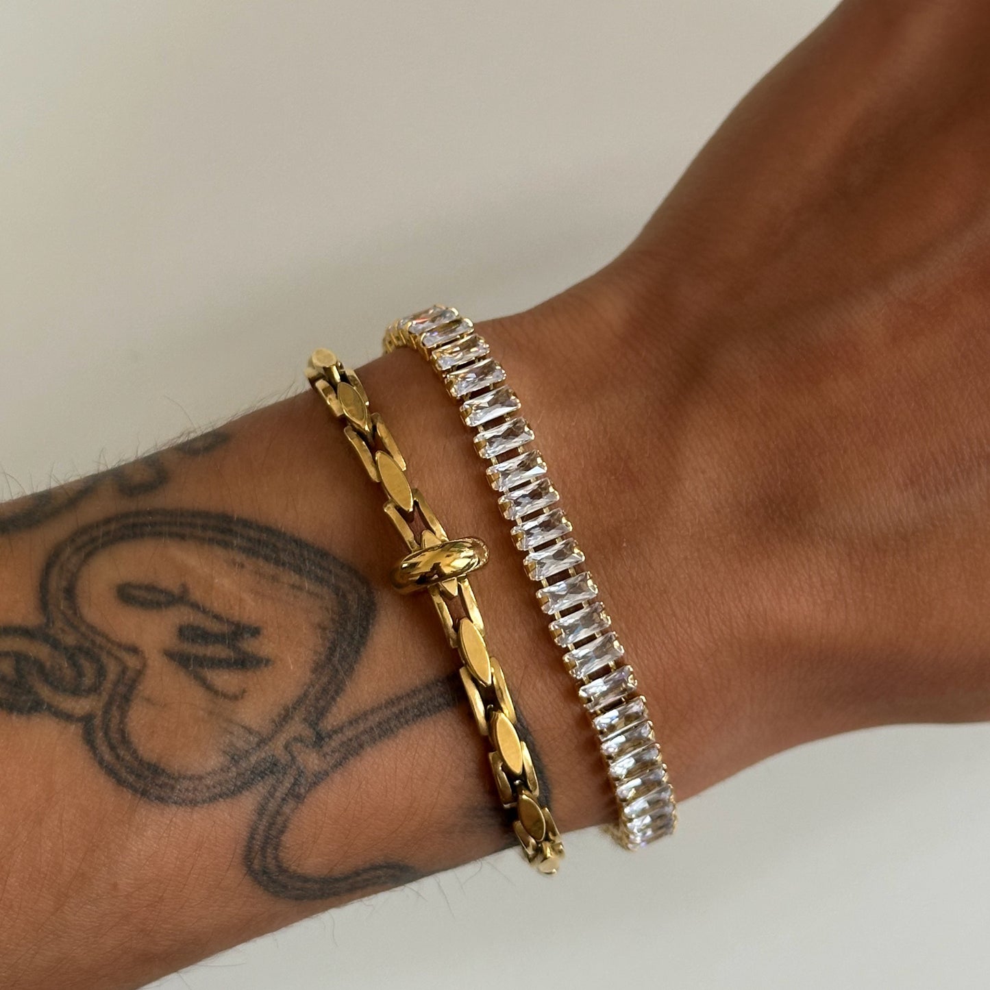 Bracelet Imany doré en acier inoxydable finition PVD or 18K porté au poignet.