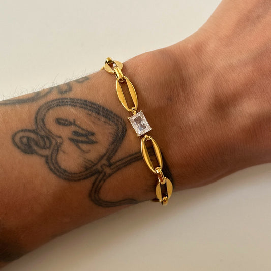 Bracelet Joey en acier inoxydable plaqué or 18K avec maillons modernes et zircon carré central porté.
