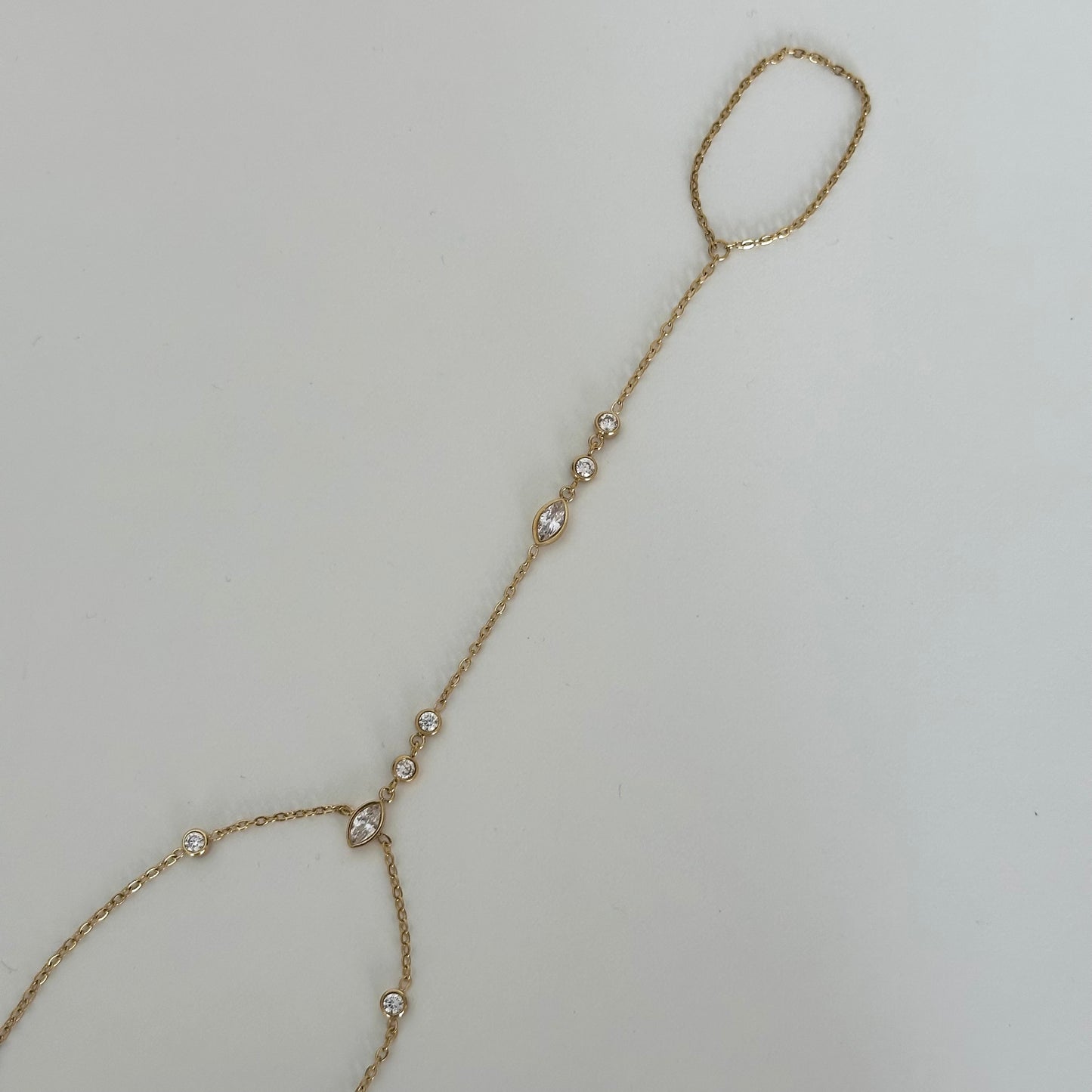 Chaîne de main Moana en acier inoxydable doré avec zircons étincelants et détail navette.