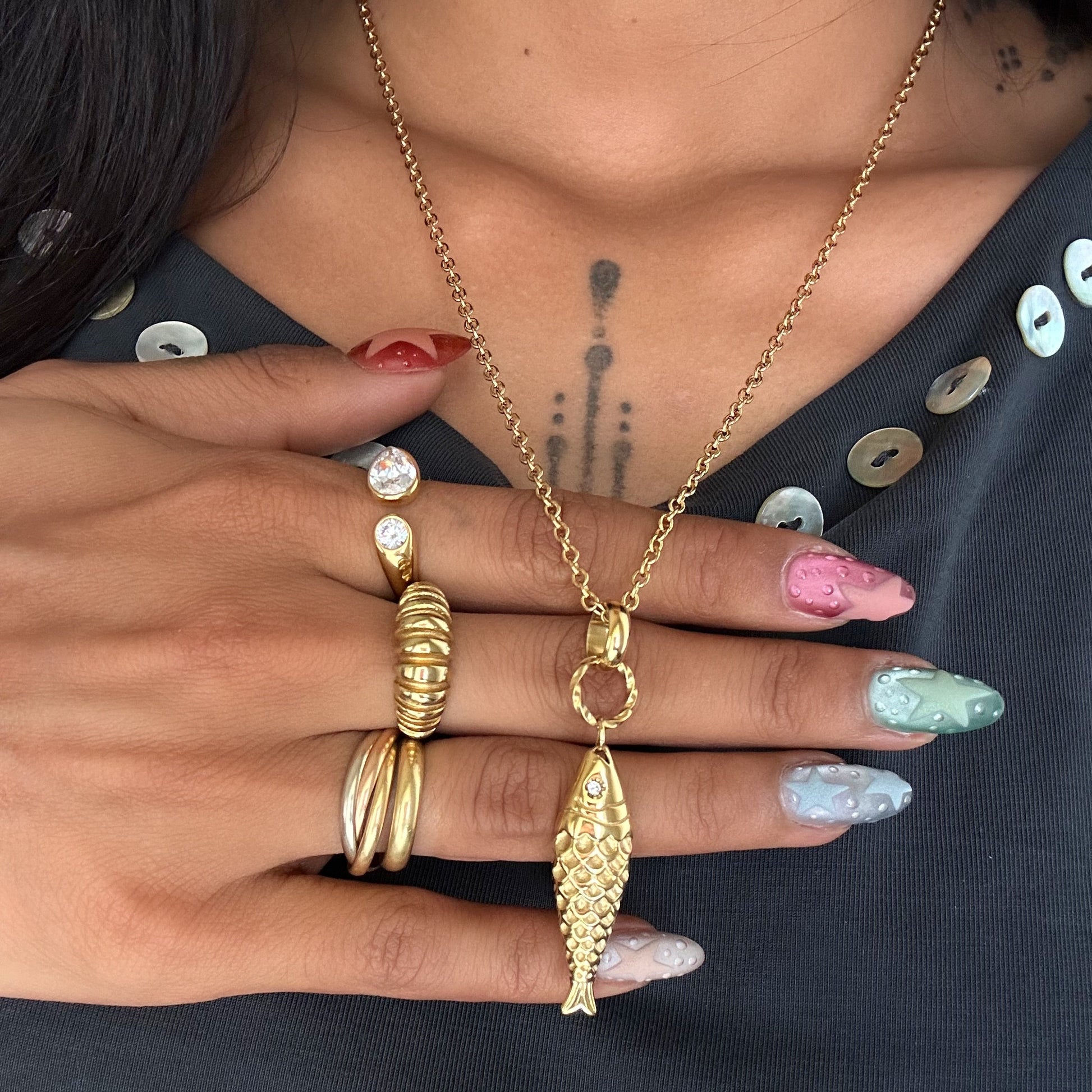 Collier Ariel en acier inoxydable doré avec pendentif poisson texturé porté.