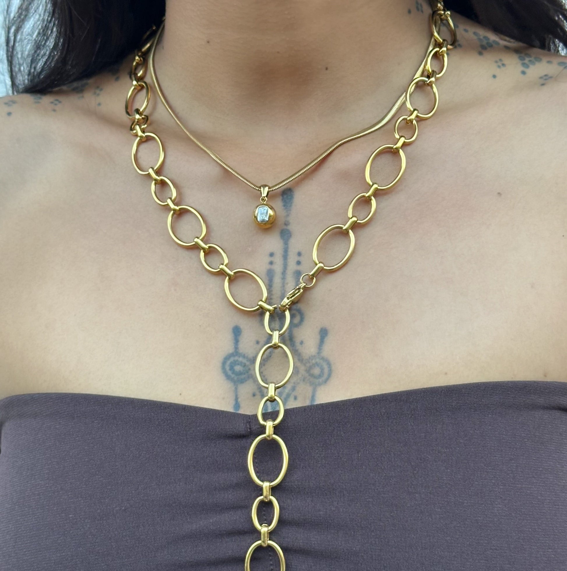 Collier Cielle en acier inoxydable doré avec pendentif boule et zircon rectangulaire porté.