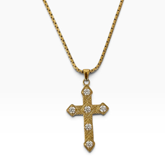 Collier Gina en acier inoxydable PVD or 18K avec pendentif croix doré orné de zircons sur fond blanc.