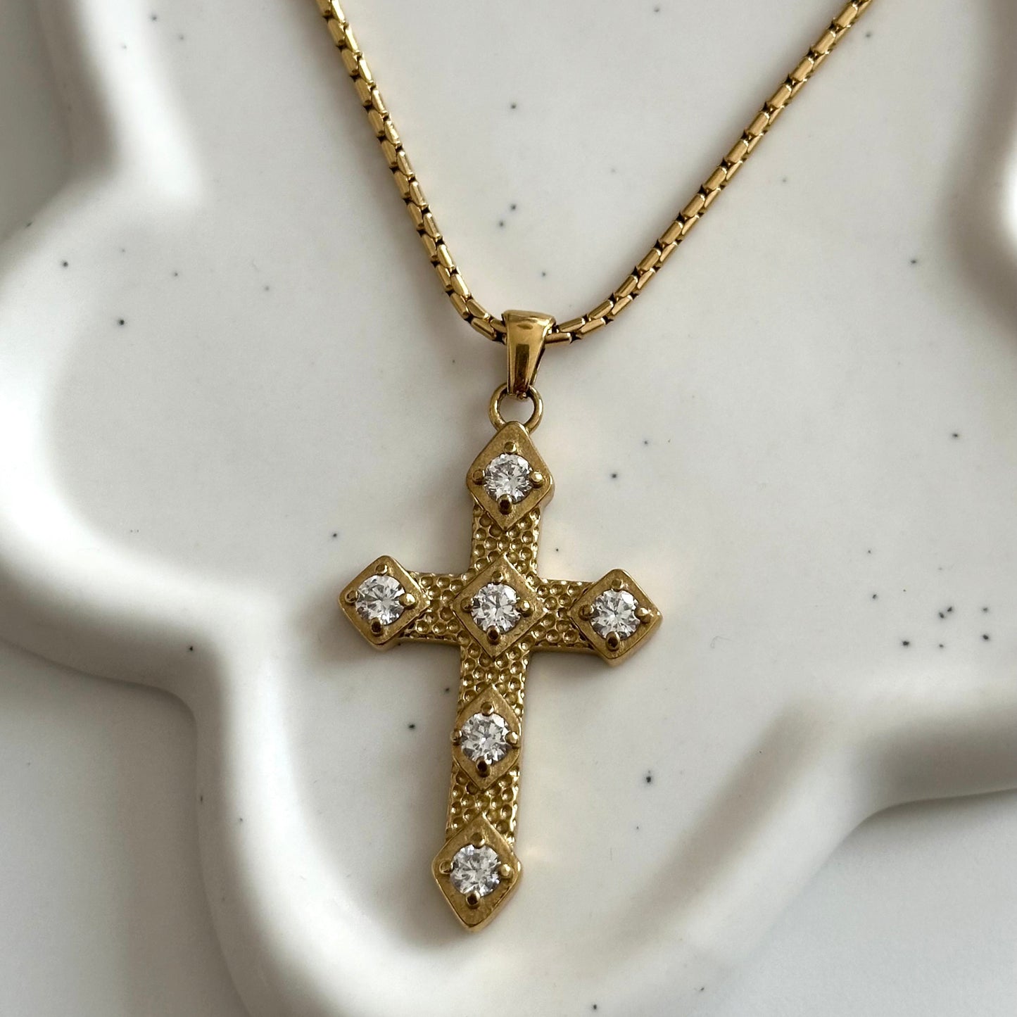 Gros plan sur le pendentif croix du collier Gina en acier inoxydable PVD or 18K, orné de zircons.