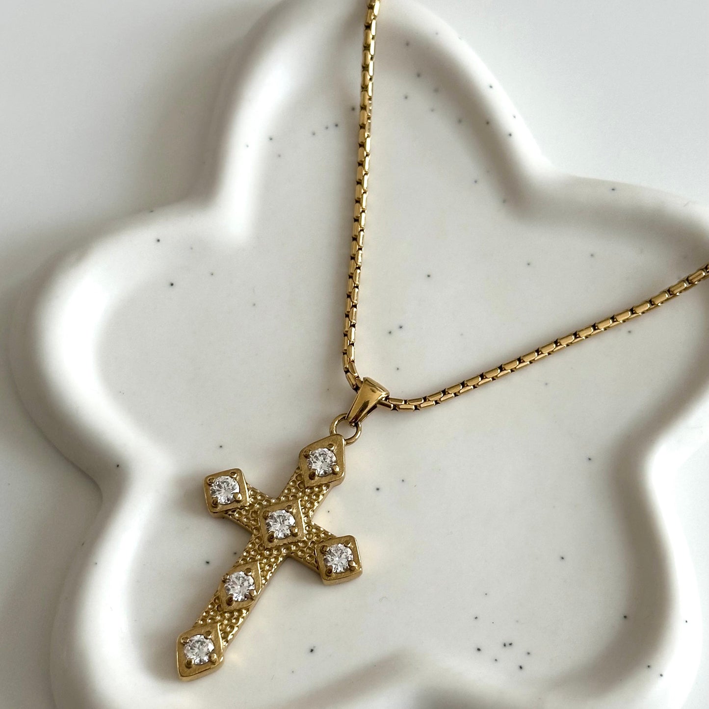 Vue rapprochée du collier Gina en acier inoxydable PVD or 18K avec pendentif croix doré serti de zircons.