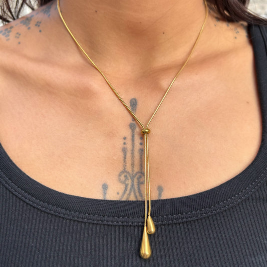 Collier Jane doré en Y avec boule coulissante et deux pendentifs en forme de goutte porté.
