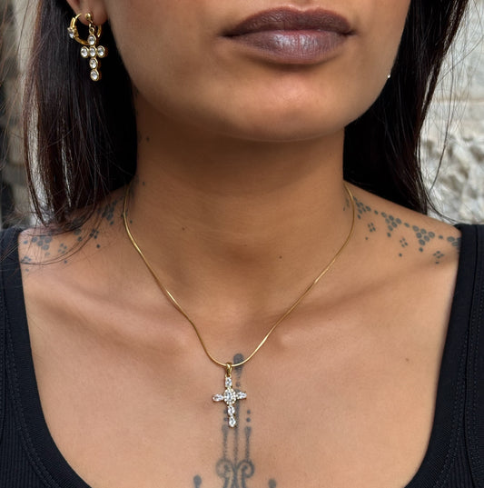 Collier Maria porté en acier inoxydable PVD or 18K avec pendentif croix serti de zircons sur fond blanc.