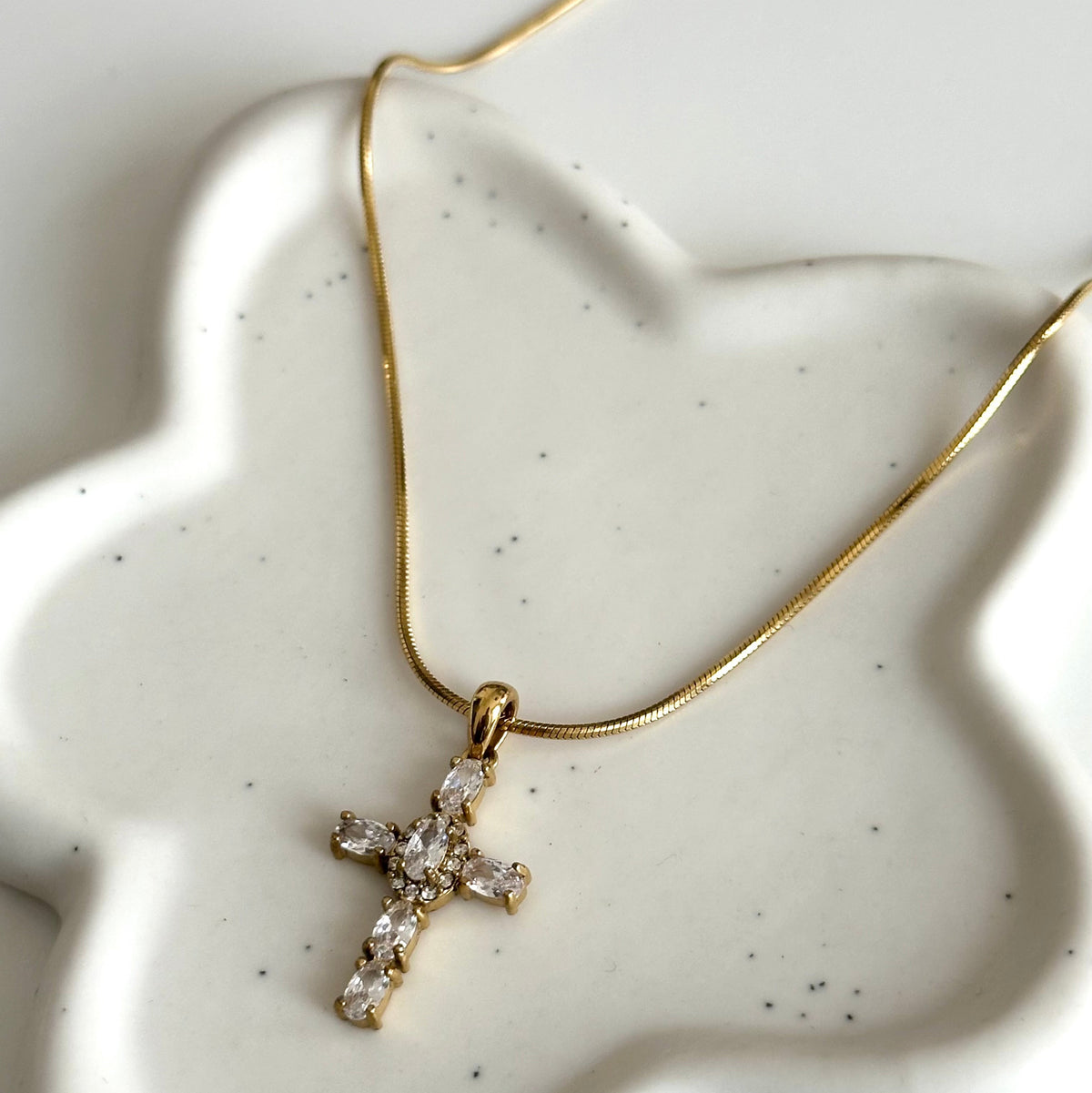 Vue rapprochée du collier Maria en acier inoxydable PVD or 18K et de son pendentif croix serti de zircons.