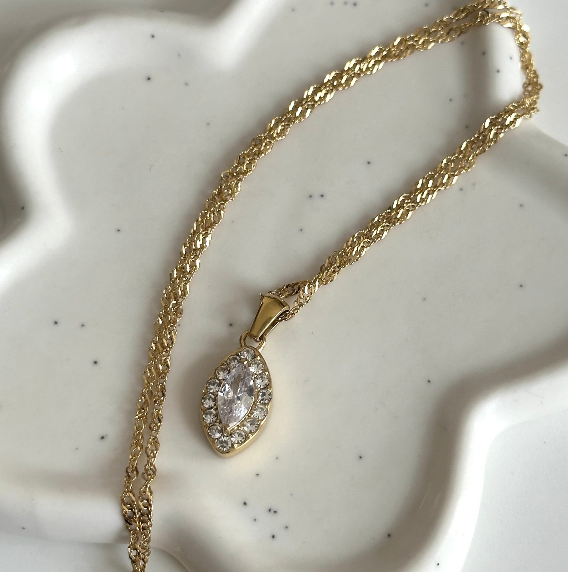 Collier Rose doré en acier inoxydable 316L posé sur support blanc, avec pendentif marquise orné de zircons.